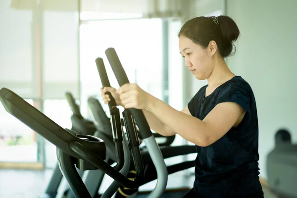 Asian fat woman using exercise machines in indoor gym, sport Asian woman\'s portrait with copy space.