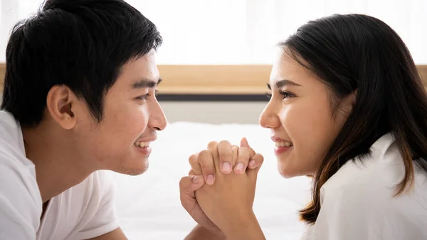 Funny and romantic Asian couple\' portrait in bedroom with natural light from window, concept of relationship between husband and wife and being a family.