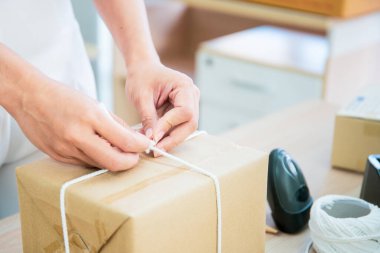 Güzel Asyalı kadın masaya bir posta paketi koyuyor, online alışveriş ve e-ticaret küçük işletme konseptinde..