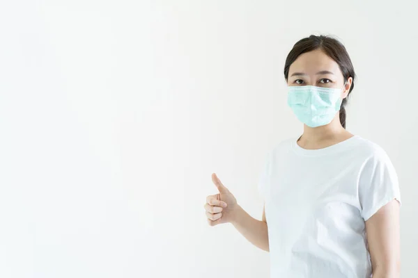 亚洲年轻貌美的女人戴着防护面罩来保护自己的脸 以防止感染流感和病毒 亚洲女人展示了一个有版权空间的大拇指 Covid19和Coronavirus爆发概念 — 图库照片