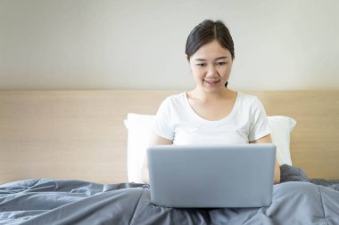 Güzel Asyalı genç bir kadın dizüstü bilgisayarını kullanarak interneti ve sosyal medyayı allak bullak ediyor. Neşeli Asyalı kız arkadaşıyla sohbet etmek için sosyal medyayı kullanıyor..