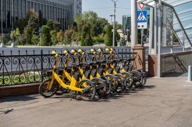 September 14 2025, Tashkent Uzbekistan: Row of shared yellow electric scooters parked near a metro entrance.