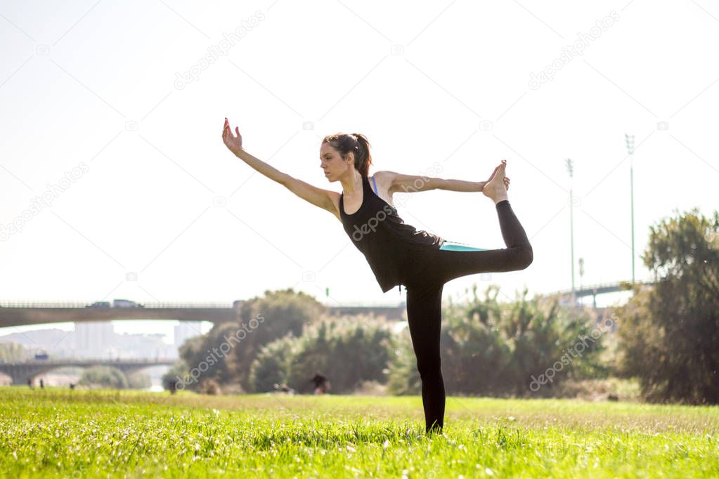 Young athletic woman practicing hatha yoga postures wearing leggings and pigtail