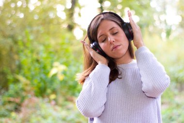 Doğa veya ormandaki ağaçlar ile kask ellerde çok sakin zen müzik dinlerken huzur çevrili beyaz Avrupa Genç kadın veya kız rahat