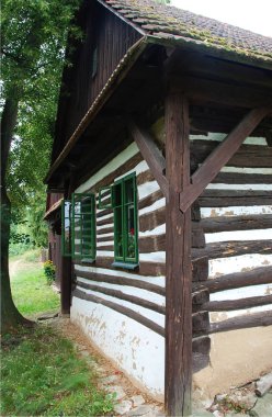 Geleneksel eski ahşap evi büyük ağacın arkasına gizlenmiş Yesil pencereli 