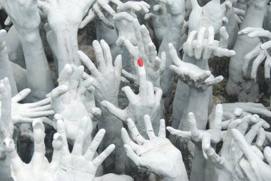 Wat Rong Khun takma Chiang Rai, Tayland Beyaz Tapınak etrafında kırmızı çivi ile eller ve orta parmak Closeup görünümü 