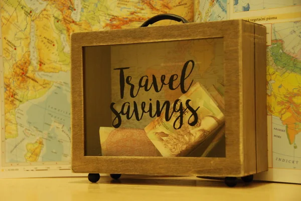 世界地図の背景にスーツケース形のお金箱で旅行するためのお金の節約 — ストック写真