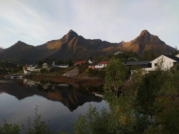 挪威罗弗顿群岛上的斯沃尔维尔市和湖中映照的四周山脉 — 图库照片