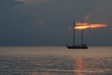 Gün batımında okyanusta yelkenli tekne