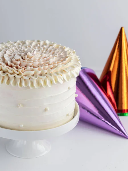 中立的な背景にカラフルなパーティー帽子ホワイト誕生日ケーキ 垂直方向 領域をコピーします コンセプトを祝う — ストック写真