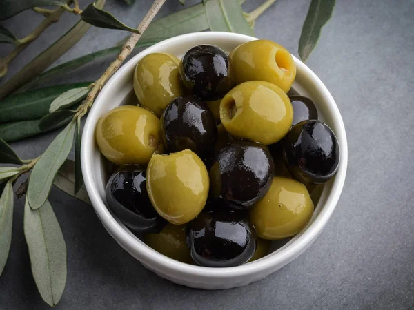 Green and black olives with Italian traditional snack grissini, rustic wooden board. Copy space.