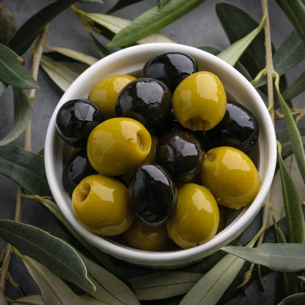 Green and black olives with Italian traditional snack grissini, rustic wooden board. Copy space.