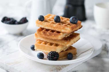 Rectangular waffles on a white plate decorated with blueberries with marbled background. copy space clipart