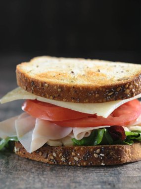 Jambon, peynir, domates ve salata karanlık bir arka plan üzerinde kızarmış ekmek üzerinde büyük sandviç.