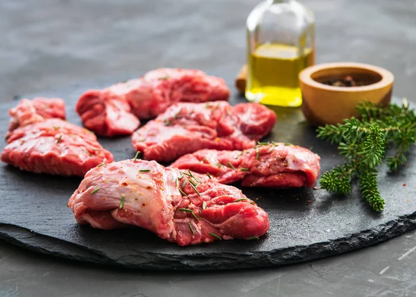 Ham yanakları domuz bir koyu gri yüzeyi biberiye ve baharatlar ile. Gıda arka plan kopya alanı ile. Yatay. Metin için yer.