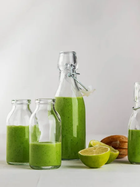 Fresh made healthy green smoothie served in bottles on white background. Fruits and vegetables and seeds ingredients around. Close with copy space. Lifestyle. Vertical.
