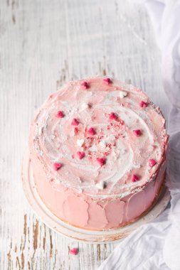 Kopya alanı ile hafif bir arka plan üzerinde sprinkles kalpleri ile küçük kalpler ile süslenmiş bir pasta Close Up. Romantik aşk konsepti. Düğün, Sevgililer Günü, Doğum Günü Anneler Günü, Kek kartı Arka Plan.