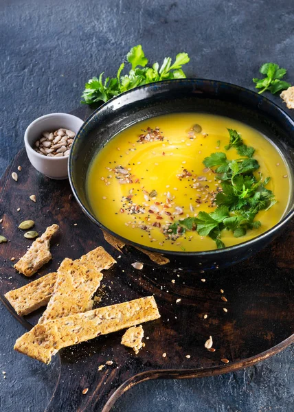 Pompoen en groenten Roomsoep met pompoenpitten, schijfjes brood en peterselie over een donkere achtergrond met ruimte voor tekst. Vegan Food concept. Hard zonlicht, harde schaduwen, bovenaanzicht. — Stockfoto