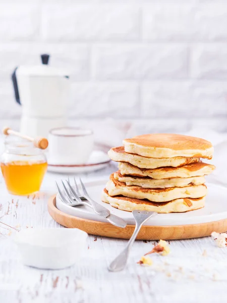 Stack av gyllene läckra pannkakor, honung, kaffe på vit bakgrund med kopierings utrymme. Romantisk frukost och traditionell mat till Fettisdagen. Amerikansk mat, selektivt fokus. — Stockfoto