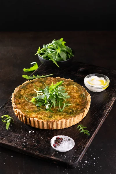 Ispanak, arugula ve peynir feta ile Quiche, copyspace ile koyu arka plan üzerinde gruyere. Ev yapımı, geleneksel Fransız quiche pasta.