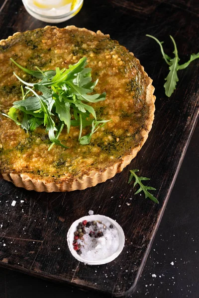 Quiche met spinazie, rucola en kaas feta, Gruyere op donkere achtergrond met copyspace. Zelfgemaakte, traditionele Franse quiche Pie. — Stockfoto