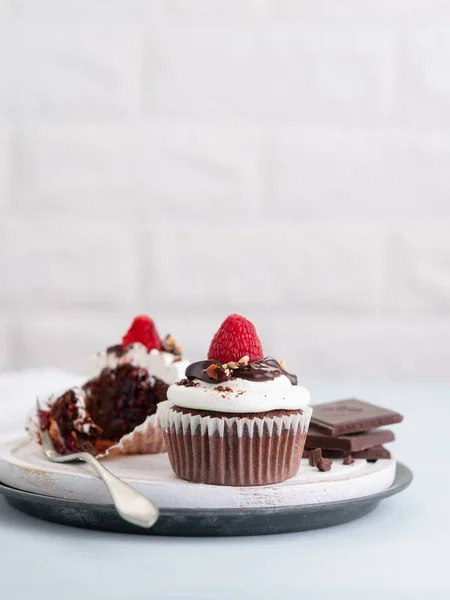 Magdalenas de chocolate con una taza de café y frambuesas frescas en la mesa, fondo claro con texto de espacio . —  Fotos de Stock