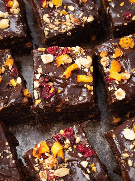 Chocolate brownie cake, dessert with nuts and fruits on dark background, directly above. Diet concept, vegan. — Stock Photo, Image