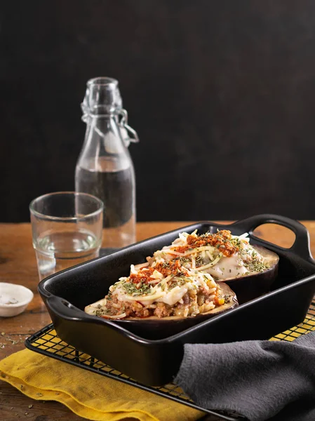 Gevulde geroosterde aubergine, brinjal of aubergine met een vlees- en vegetarische vulling en hartige bechamel op een houten tafel met ruimte voor tekst. Mediterrane keuken, Spaans recept. Etenswaren. — Stockfoto