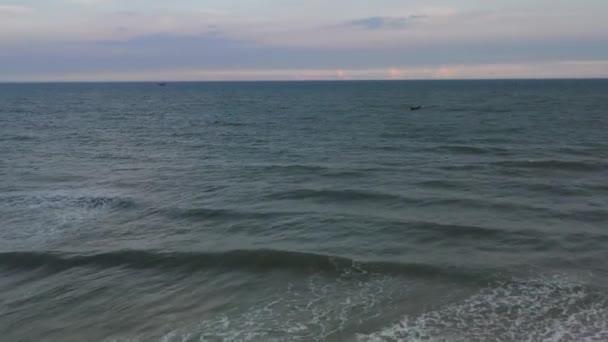 从空中俯瞰大海 无人机在黑暗的海面上低空飞行 带着柔和的云彩进入地平线 日落时在海里的渔船 — 图库视频影像