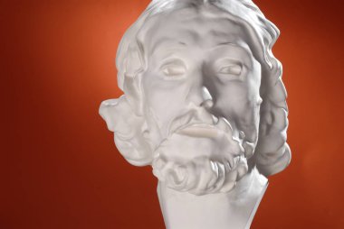 Turuncu bir arka plan üzerinde antik tarzda baş beyaz heykel