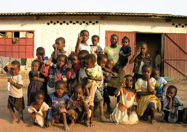 Lubumbashi, Demokratik Kongo Cumhuriyeti, ca. Mayıs 2006: Terk edilmiş bir fabrikanın bahçesinde kameraya poz veren bir grup çocuk ve kadın