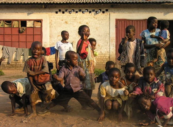 Lubumbashi, Demokratik Kongo Cumhuriyeti, ca. Mayıs 2006: Terk edilmiş bir fabrikanın bahçesinde kameraya poz veren bir grup çocuk ve kadın
