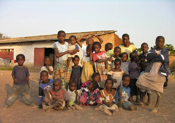 Lubumbashi, Demokratik Kongo Cumhuriyeti, ca. Mayıs 2006: Terk edilmiş bir fabrikanın bahçesinde kameraya poz veren bir grup çocuk ve kadın