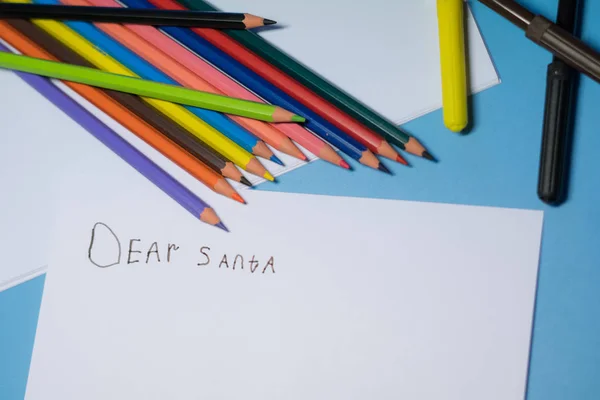 Little girl with pencils and felt-tip pens is writing a letter to Santa