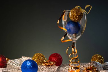 Yılbaşı kartları. Kopya alanı ile koyu arka plan üzerinde kırmızı, mavi ve altın Noel süslemeleri ile şarap kadehi.