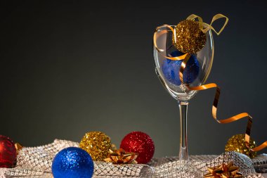 Yılbaşı kartları. Kopya alanı ile koyu arka plan üzerinde kırmızı, mavi ve altın Noel süslemeleri ile şarap kadehi.