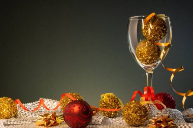 Yılbaşı kartları. Kopya alanı ile koyu arka plan üzerinde kırmızı ve altın Noel süslemeleri ile şarap kadehi.