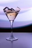 Koktejlové sklenice s pitím a ledu kostky v neonovém světle nočního klubu