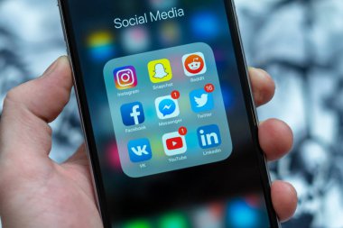 Tallinn / Estonya - 01/19/2019: Erkek el ile sosyal medya simgeler siyah elma iphone tutarak: instagram, youtube, reddit, facebook, twitter, snapchat uygulama üstünde perde. Sosyal Medya Icons.