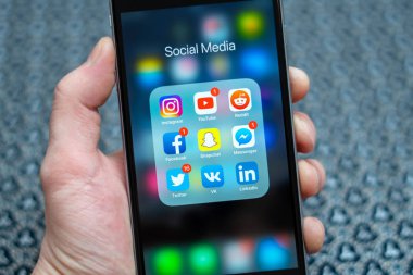 Tallinn / Estonya - 01/19/2019: Erkek el ile sosyal medya simgeler siyah elma iphone tutarak: instagram, youtube, reddit, facebook, twitter, snapchat uygulama üstünde perde. Sosyal Medya Icons.