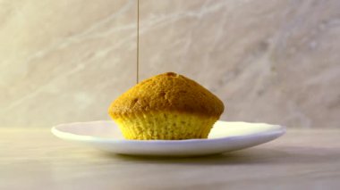 Taze pişmiş kek bir plaka üzerinde eritilmiş çikolata sosu dökerek. Damlama çikolata. Mermer arka plan ve doğal aydınlatma iç mutfakta. Organik doğal maddeler.