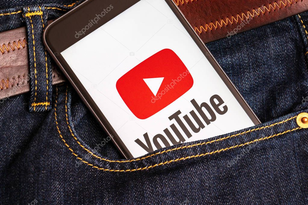 Tallinn / Estonia - 02/22/2019: Black phone with red logo of social media YouTube on the screen. Social media icon. Denim jeans background
