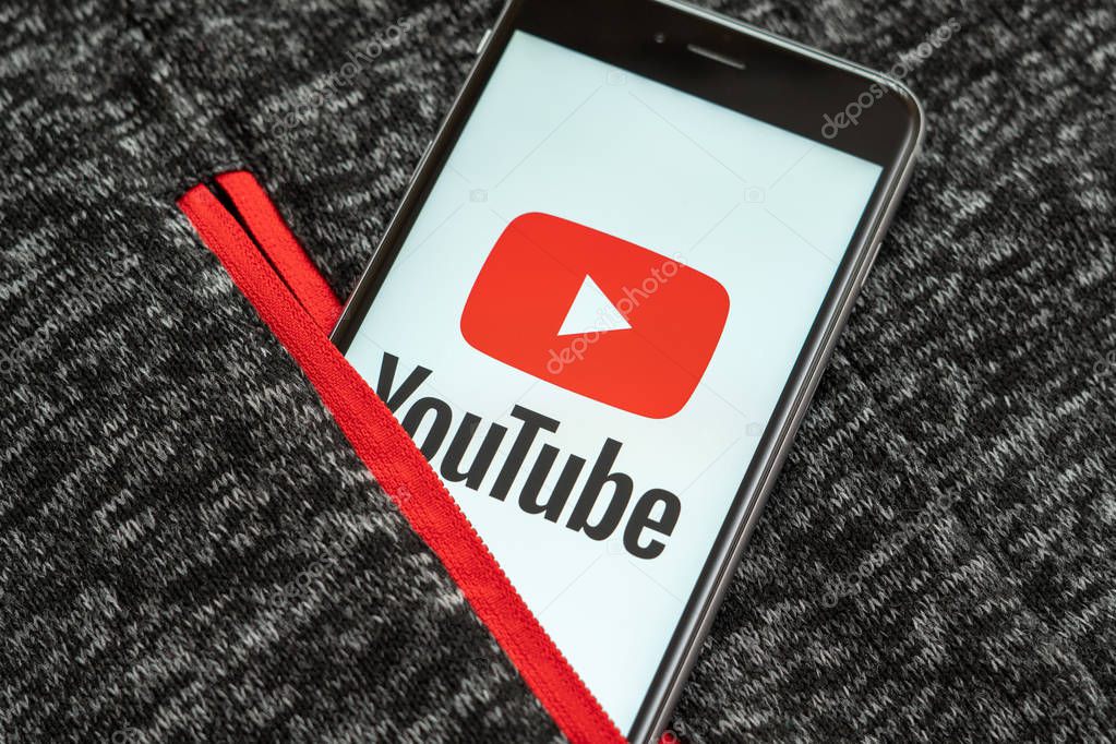 New York / USA - 02/23/2019: Black phone with red logo of social media YouTube on the screen. Social media icon. Sport clothing background