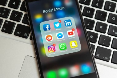 Sosyal Medya simgeler ile siyah elma iphone: instagram, youtube, reddit, facebook, twitter, snapchat, whatsapp uygulamaları ekranda. Sosyal Medya simgeler. Arka üstünde MacBook klavye