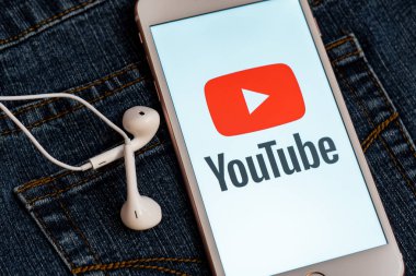 Tallinn/Estonya - 19 Mayıs 2019: Ekranda sosyal medya Youtube kırmızı logosu ile beyaz iphone. Sosyal medya simgesi. Denim kot arka plan. Pazarlama konsepti veya haber medyası illüstrasyonu.