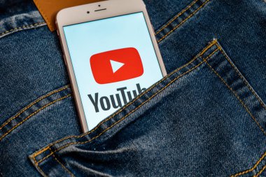 Tallinn/Estonya - 19 Mayıs 2019: Ekranda sosyal medya Youtube kırmızı logosu ile beyaz iphone. Sosyal medya simgesi. Denim kot arka plan. Pazarlama konsepti veya haber medyası illüstrasyonu.