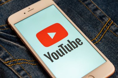 Tallinn/Estonya - 19 Mayıs 2019: Ekranda sosyal medya Youtube kırmızı logosu ile beyaz iphone. Sosyal medya simgesi. Denim kot arka plan. Pazarlama konsepti veya haber medyası illüstrasyonu.