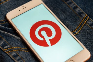 Tallinn/Estonya - 19 Mayıs 2019: Ekranda sosyal medya Pinterest logolu beyaz iphone. Sosyal medya simgesi. Denim kot arka plan. Haber medyası için pazarlama konsepti veya illüstrasyon.