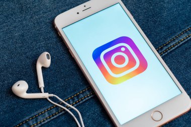 Tallinn / Estonya - 19 Mayıs 2019: Ekranda sosyal medya Instagram logosu bulunan beyaz telefon. Sosyal medya simgesi. Denim kot arka plan. Haber medyası veya pazarlama konsepti için illüstrasyon.