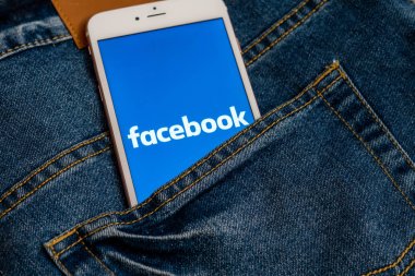 Tallinn / Estonya - 19 Mayıs 2019: Ekranda sosyal medya Facebook logosu ile beyaz iphone. Sosyal medya simgesi. Denim kot arka plan. Haber medyası için pazarlama konsepti veya illüstrasyon.